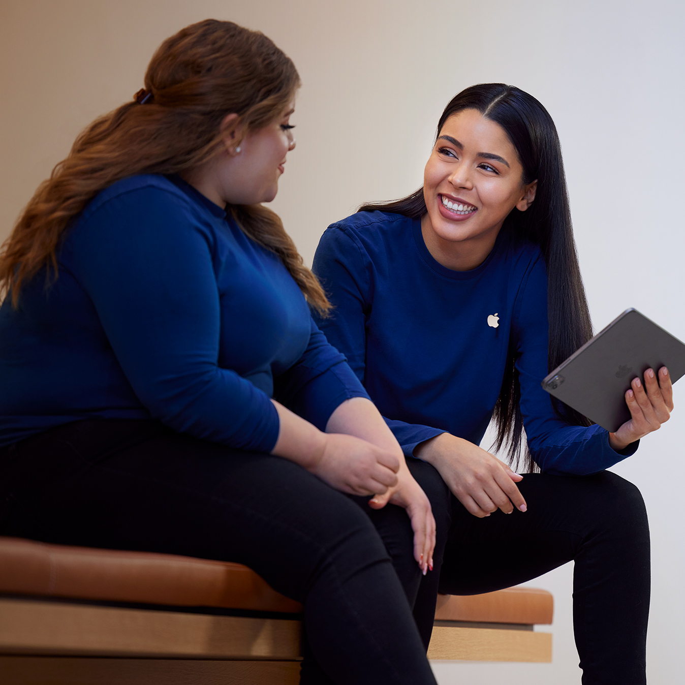 Carissa holding an iPad and talking with another Apple Retail employee.