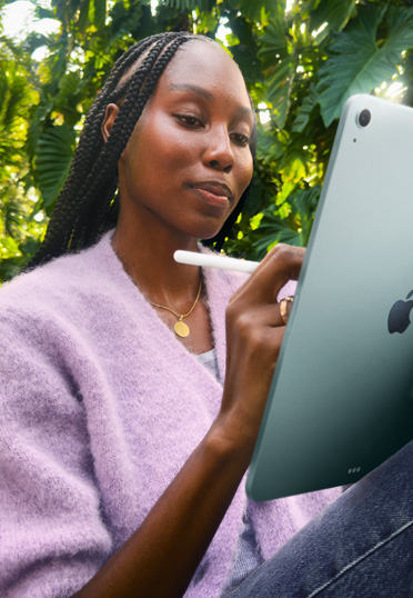 Une étudiante est assise à l’extérieur. Elle tient un iPad et un Apple Pencil Pro.