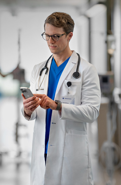Um profissional de saúde consulta seu iPhone para analisar o progresso de um paciente no ambiente hospitalar.