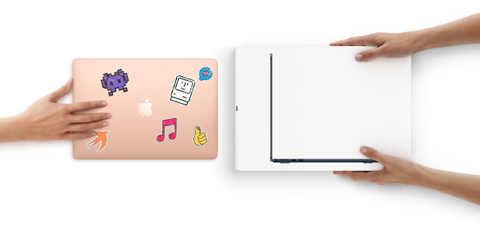 A hand slides a MacBook with stickers on the cover toward two hands holding a new MacBook in the box