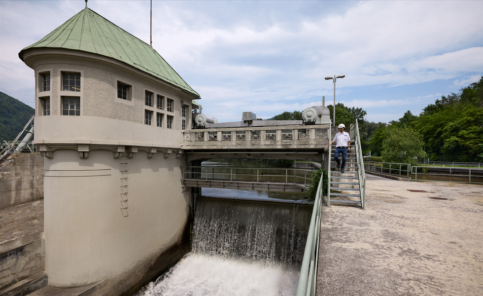 An employee wearing a safety hat descends stairs from a bridge at a hydropelectric facility
